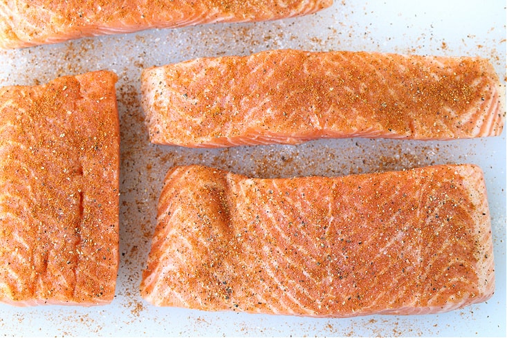 salmon filets with seasoning on a cutting board
