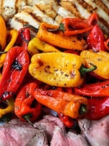 Mini roasted peppers on a platter with grilled chicken and steak