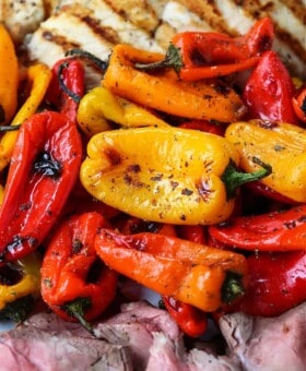 Mini roasted peppers on a platter with grilled chicken and steak