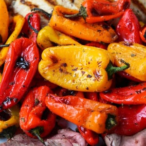 Mini roasted peppers on a platter with grilled chicken and steak