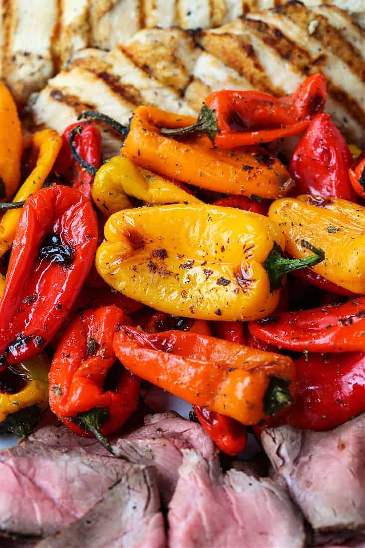 Mini roasted peppers on a platter with grilled chicken and steak