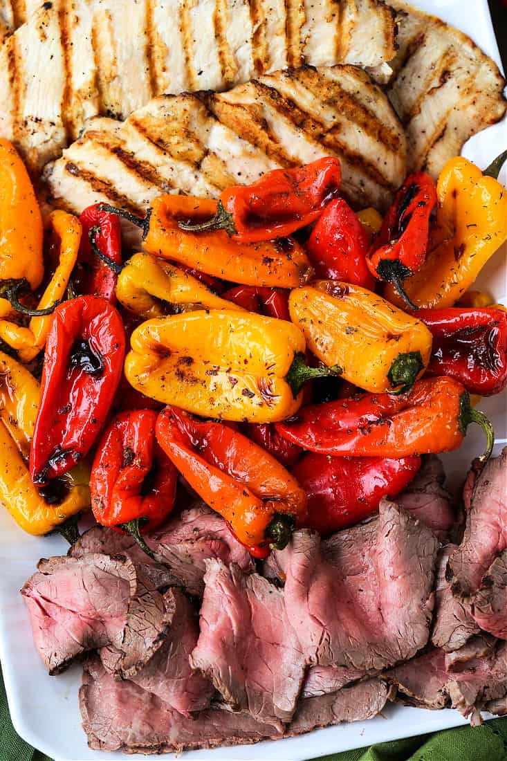 Mini roasted peppers on a platter with grilled chicken and steak