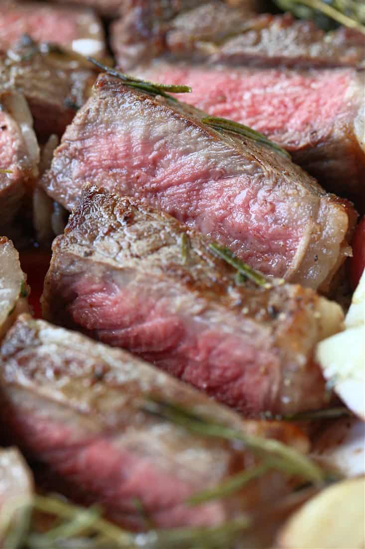 sliced new york strip steak stacked on a plate