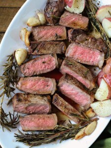 strip steak sliced on a platter with potatoes