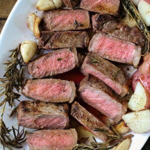 strip steak sliced on a platter with potatoes