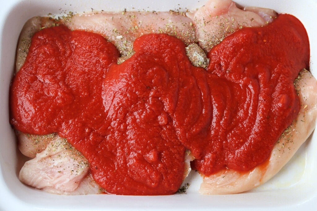 Slow Cooker Chicken Parmesan Sandwiches are an easy dinner for any night of the week! Perfect for meal prepping, game days or holidays! seasoned chicken breasts with marinara sauce in slow cooker