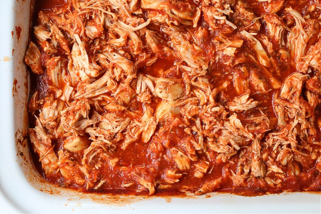 Slow Cooker Chicken Parmesan Sandwiches are an easy dinner for any night of the week! Perfect for meal prepping, game days or holidays! shredded chicken with marinara sauce in slow cooker