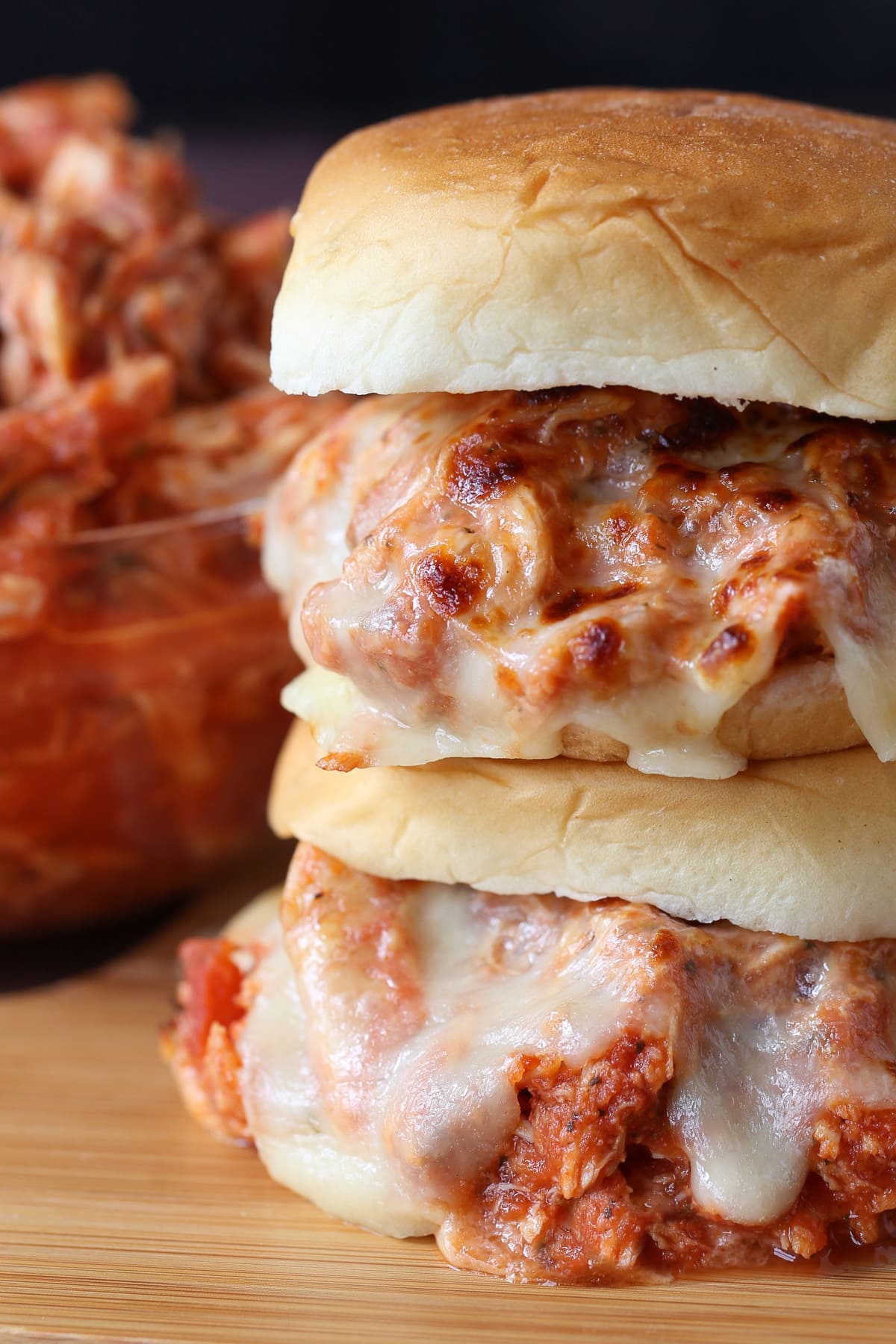 stacked sandwiches with shredded chicken and melted mozzarella cheese