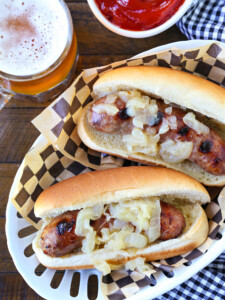 bratwurst with onions on a platter with beer and ketchup