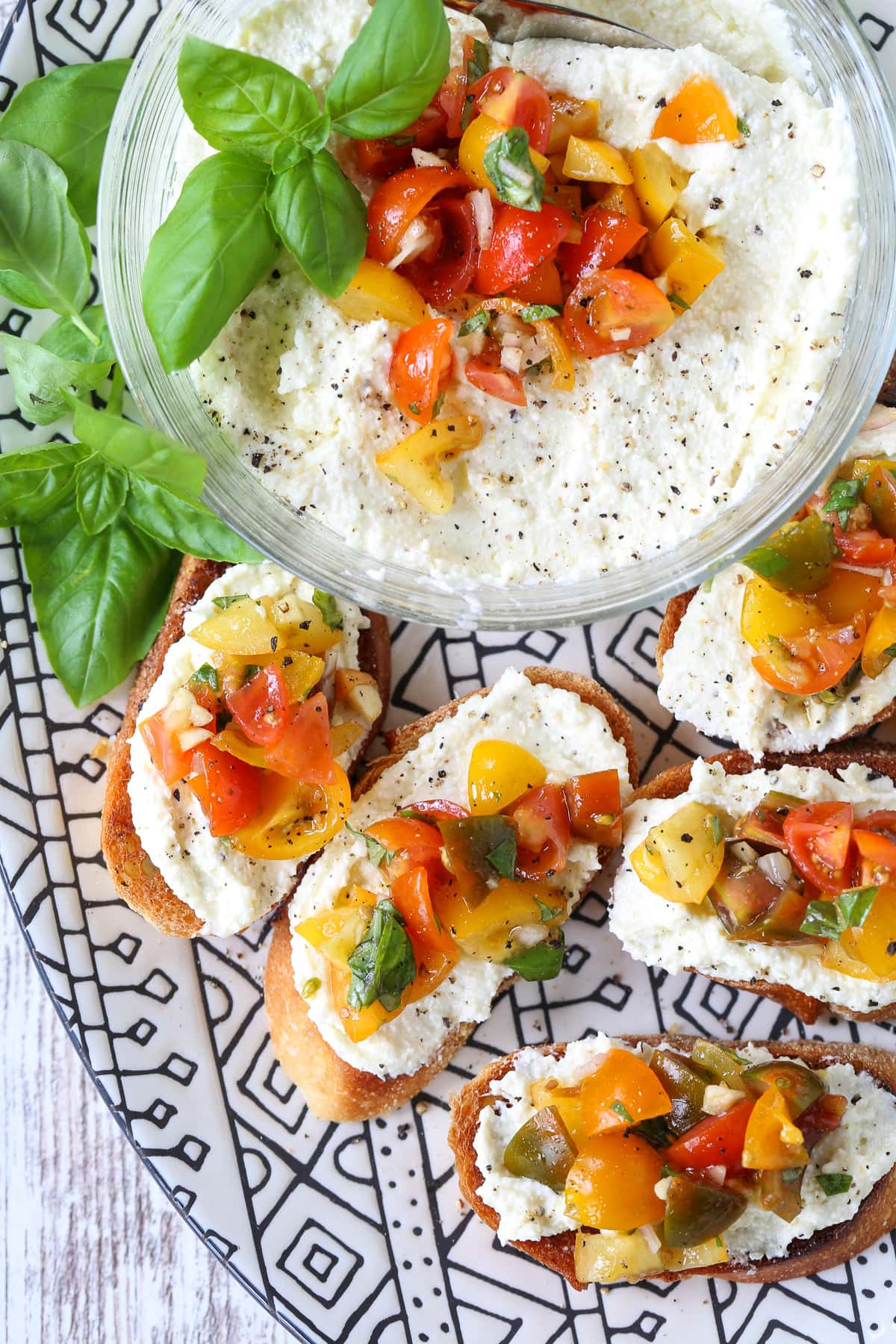 bruschetta with whipped feta on a black and white platter