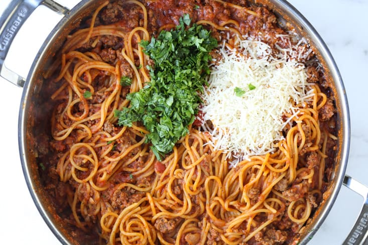 Spaghetti in a pot with fresh basil and parmesan cheese