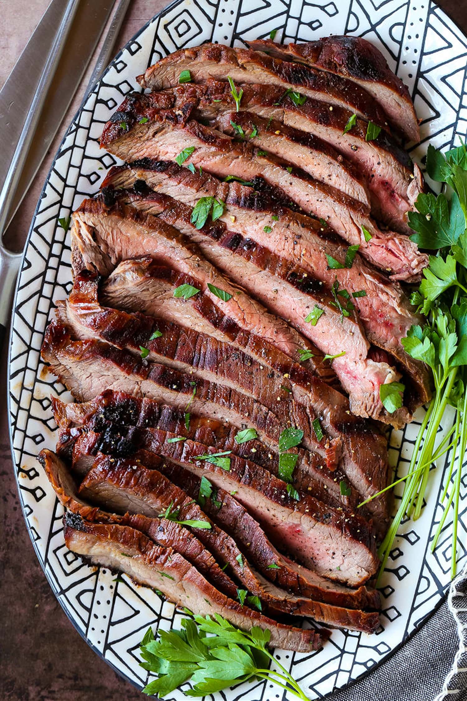 sliced flank steak on a black and white platter