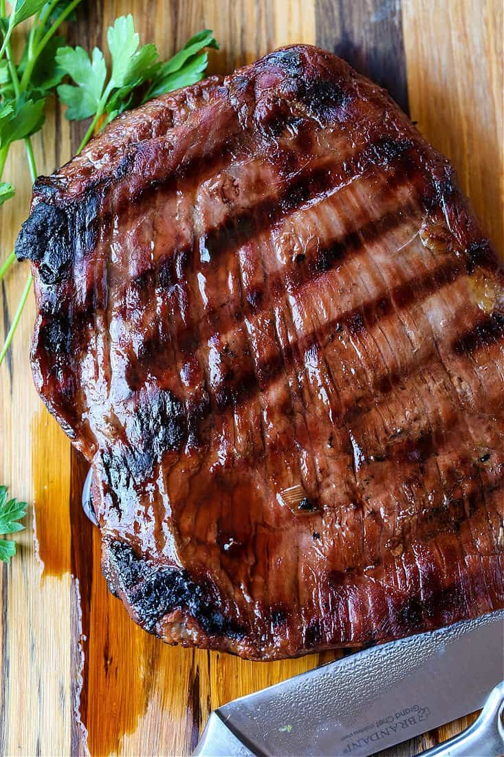 Teriyaki marinated flank steak on a board with knife