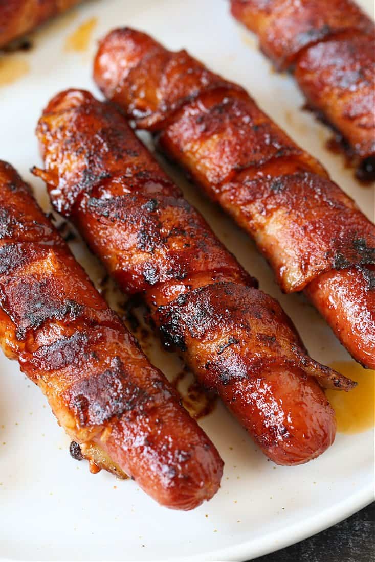 bacon wrapped hot dogs on a plate