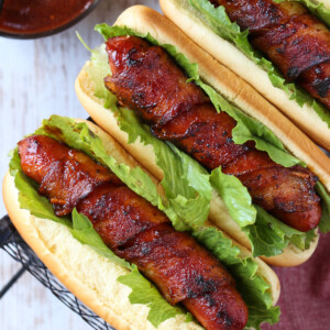 hot dogs wrapped with bacon on buns with lettuce