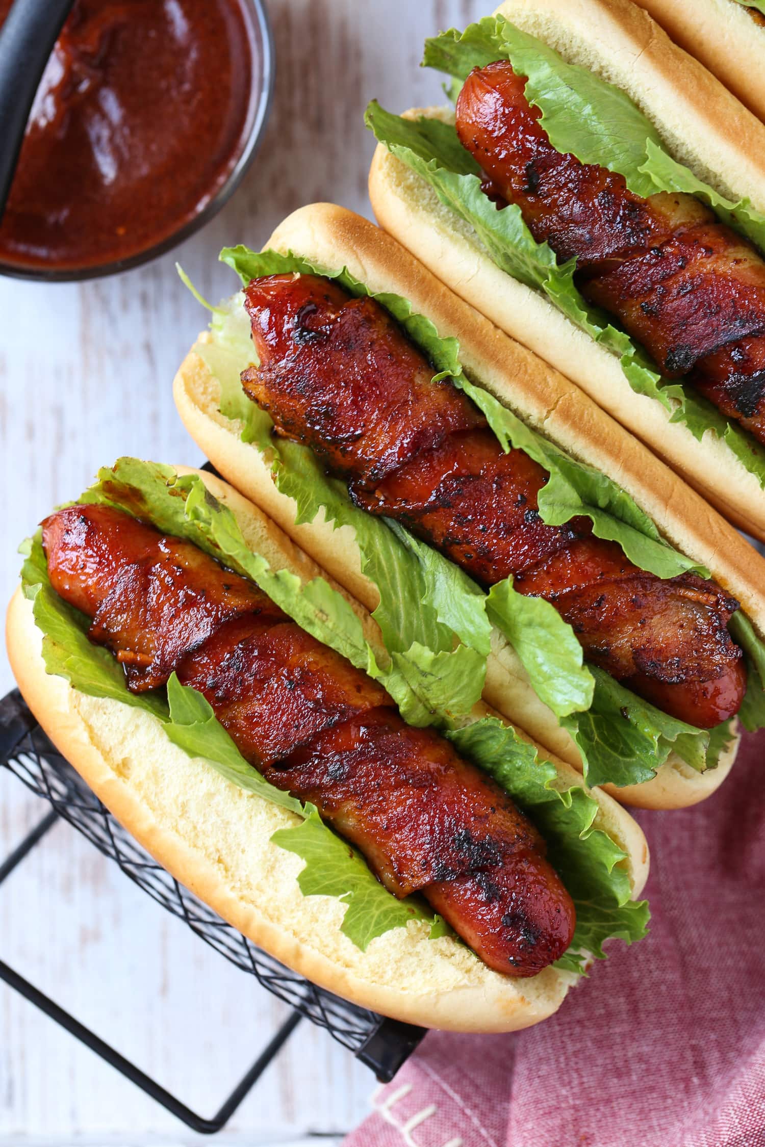 hot dogs wrapped with bacon on buns with lettuce