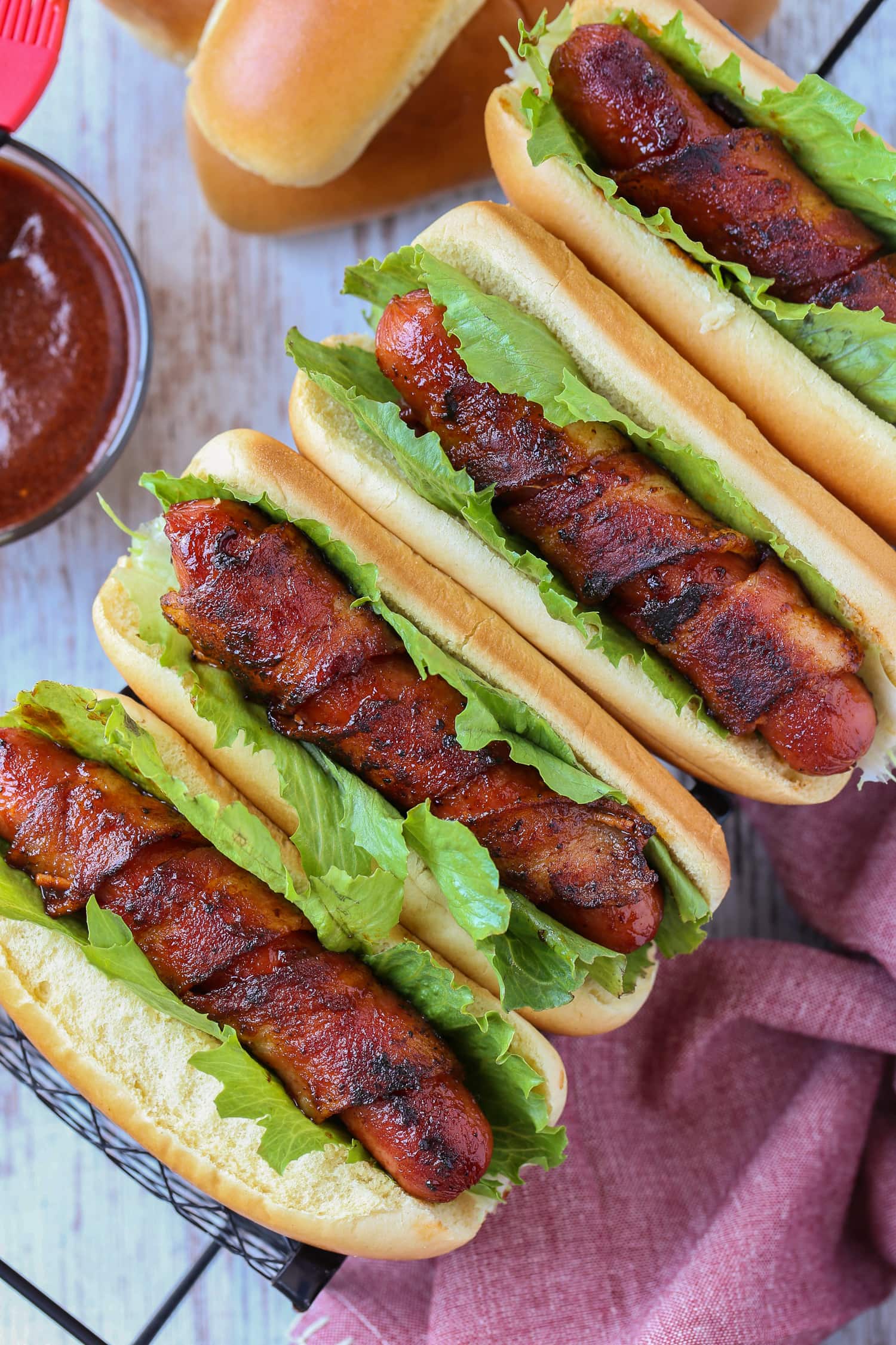 bacon wrapped hot dogs on buns with lettuce