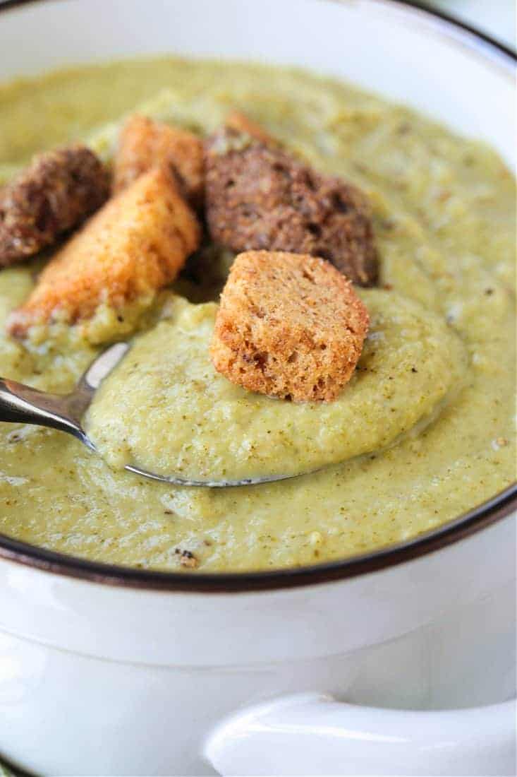 Cozy up to a bowl of this delicious Cream of Broccoli Soup! A nutritious soup recipe that gives you a luxurious, indulgent feel! cream of broccoli soup with a spoon and croutons