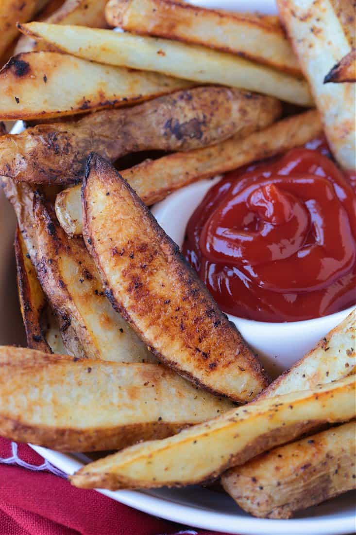 Crispy Baked Steak Fries are a delicious side dish to almost any meal! Soft, fluffy, tender insides with a crispy, perfectly seasoned crust! steak fries in a bowl with ketchup