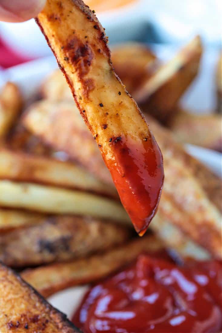 Crispy Baked Steak Fries are a delicious side dish to almost any meal! Soft, fluffy, tender insides with a crispy, perfectly seasoned crust! french fry dipped in ketchup