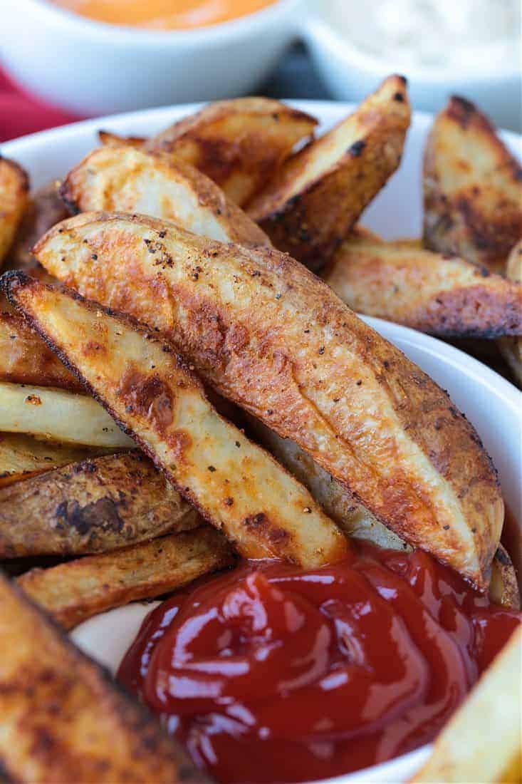 Crispy Baked Steak Fries are a delicious side dish to almost any meal! Soft, fluffy, tender insides with a crispy, perfectly seasoned crust! steak fries in a serving bowl with ketchup