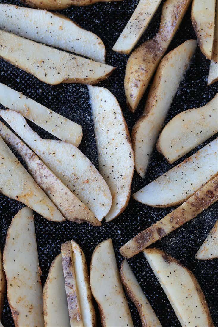 potato wedges cut into fry shapes on a baking sheet