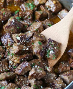 steak bites in garlic butter sauce with wooden spoon