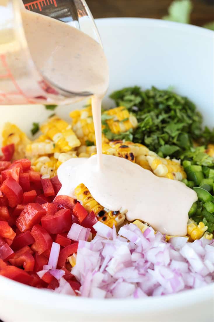 dressing being poured onto a vegetable salad