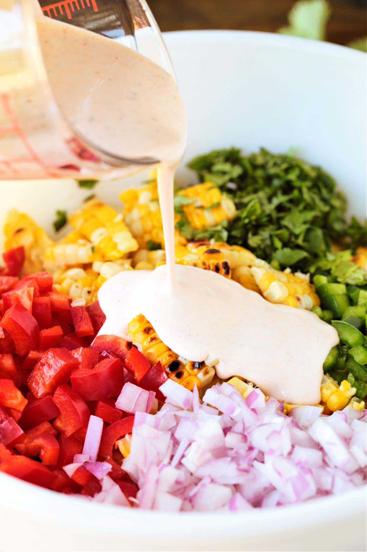 dressing being poured onto a vegetable salad