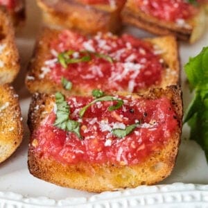 Pan con tomate on a white serving platter with fresh basil