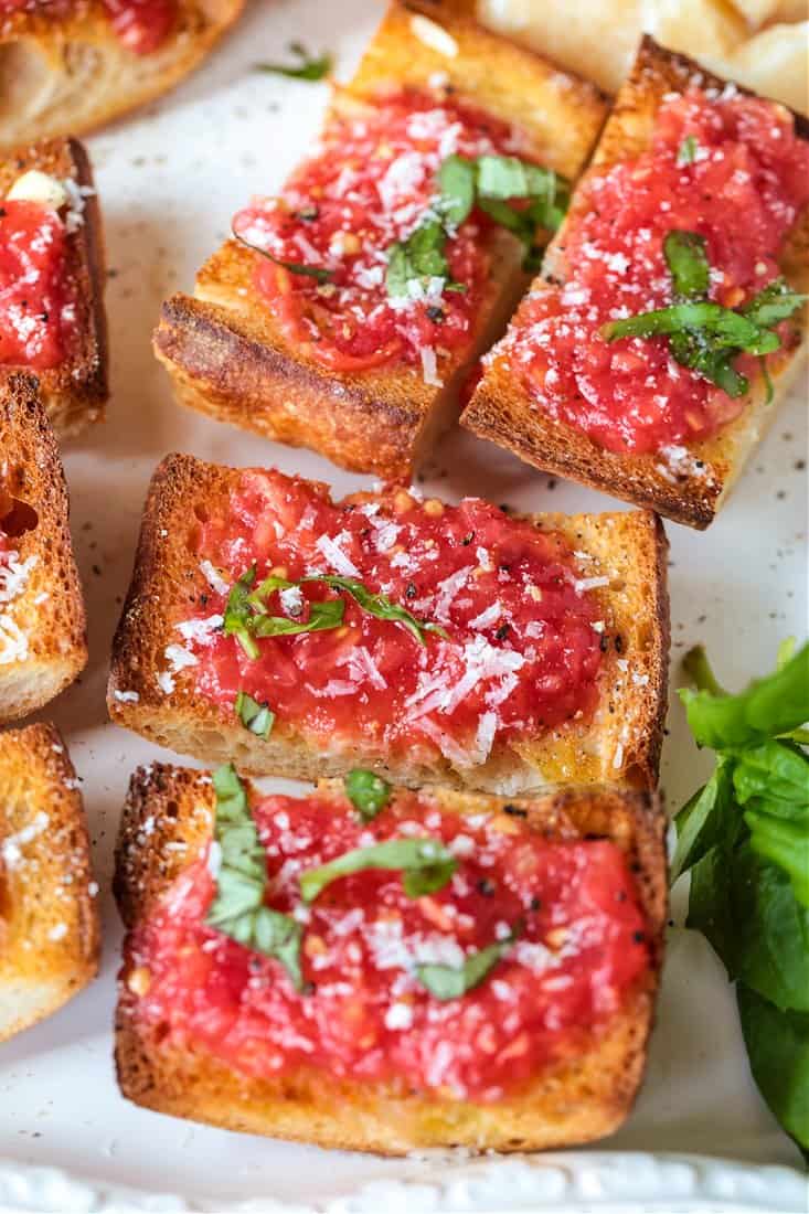 pan con tomate topped with fresh basil and parmesan cheese