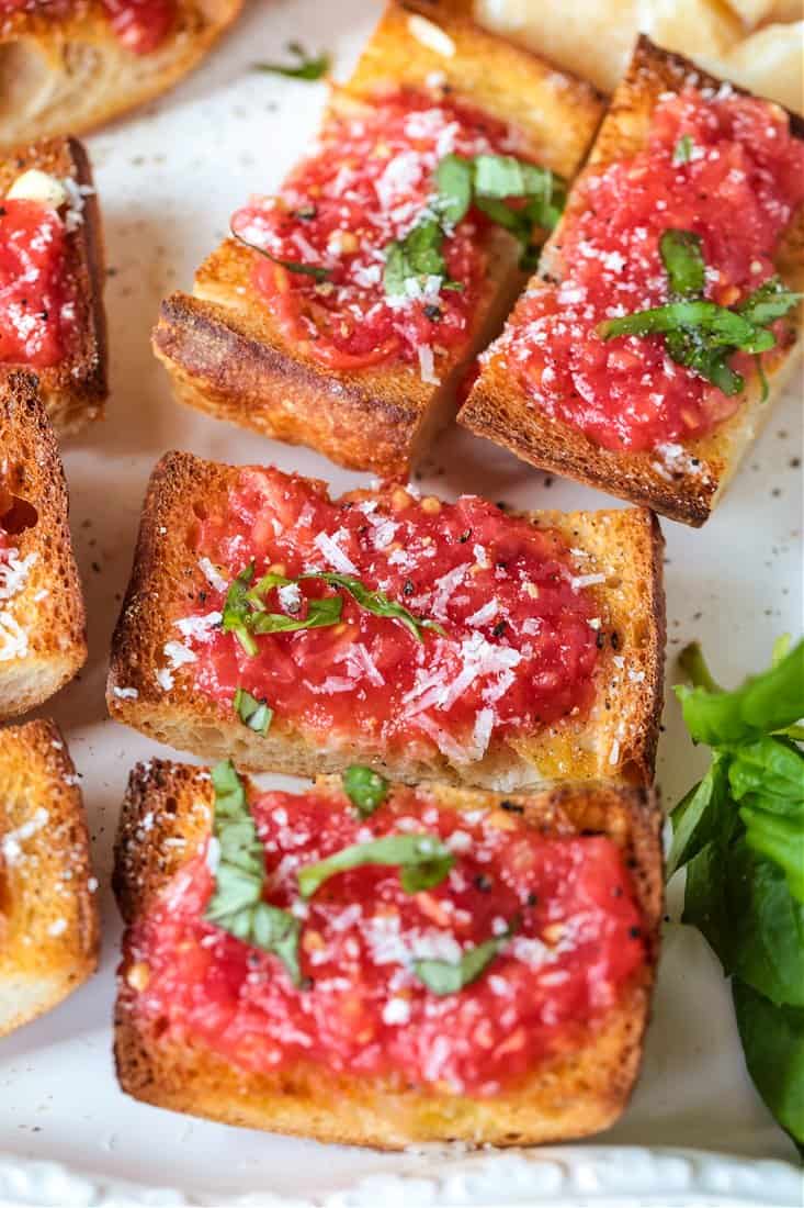 pan con tomate topped with fresh basil and parmesan cheese