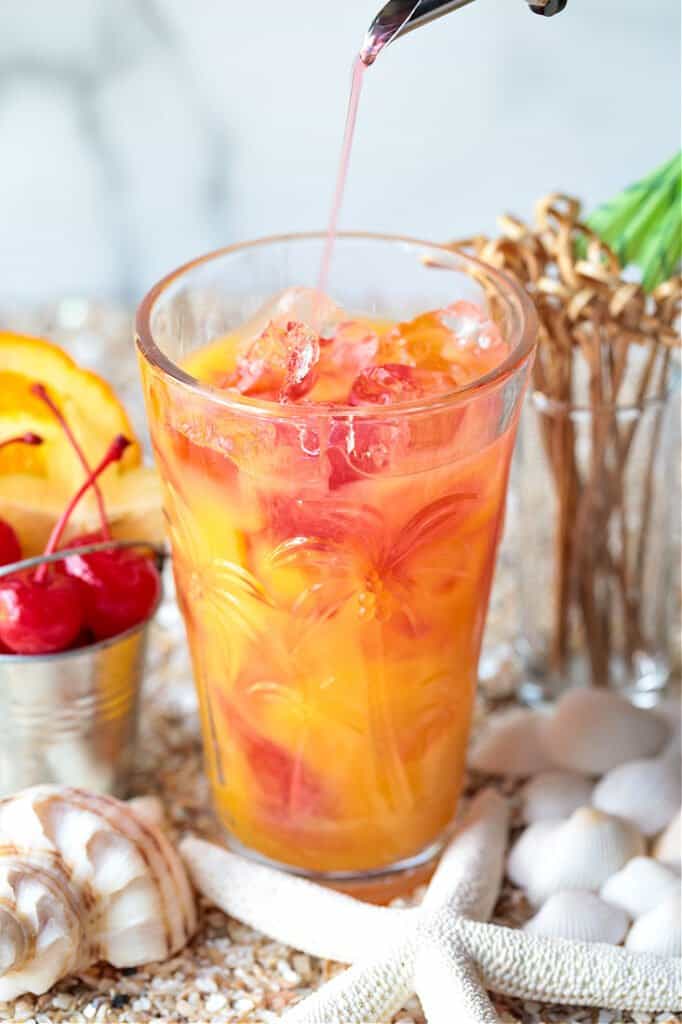 cranberry juice being poured into a glass with orange juice and vodka