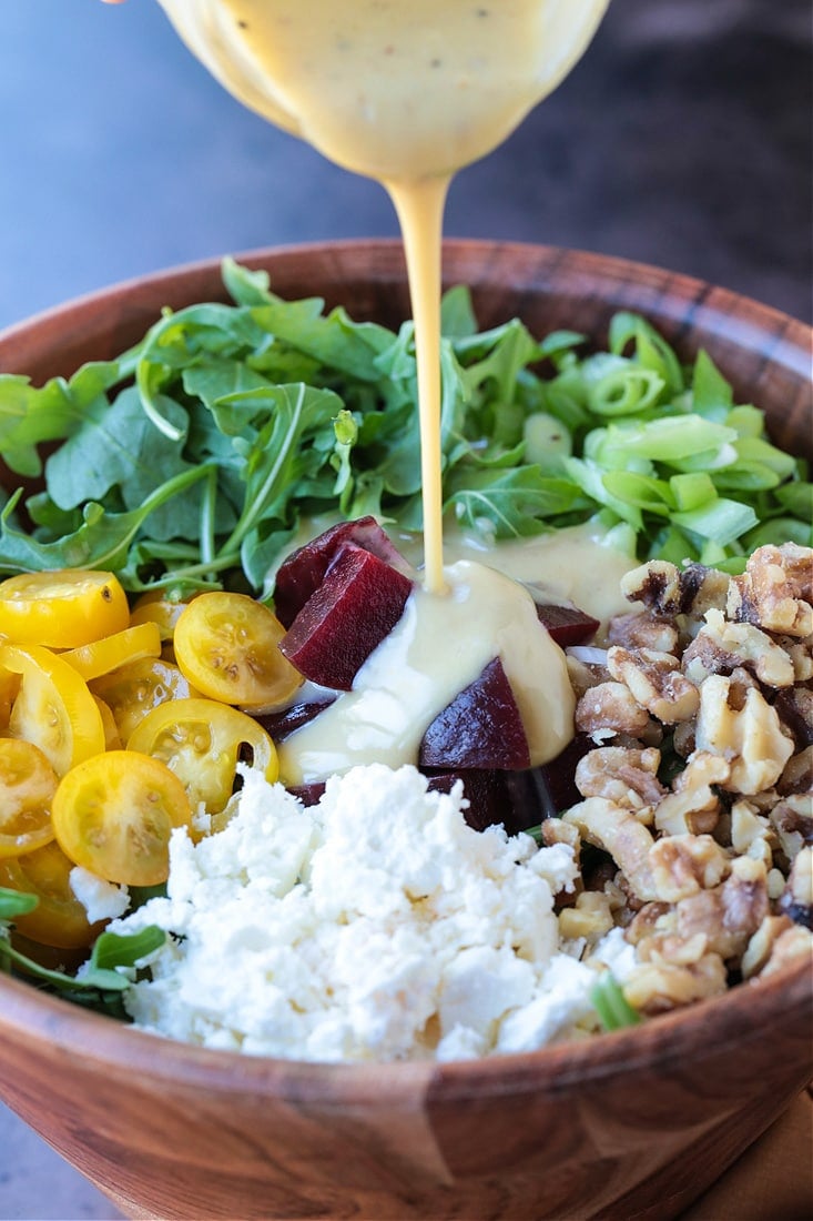 arugula salad with maple dressing being poured on top