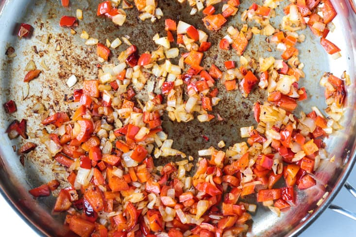 peppers and onions cooking in a skillet for steak sandwiches