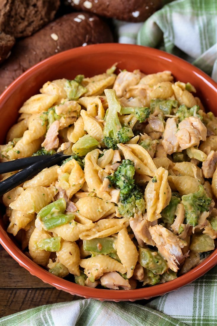 Chicken broccoli pasta in bowl with rolls and forks