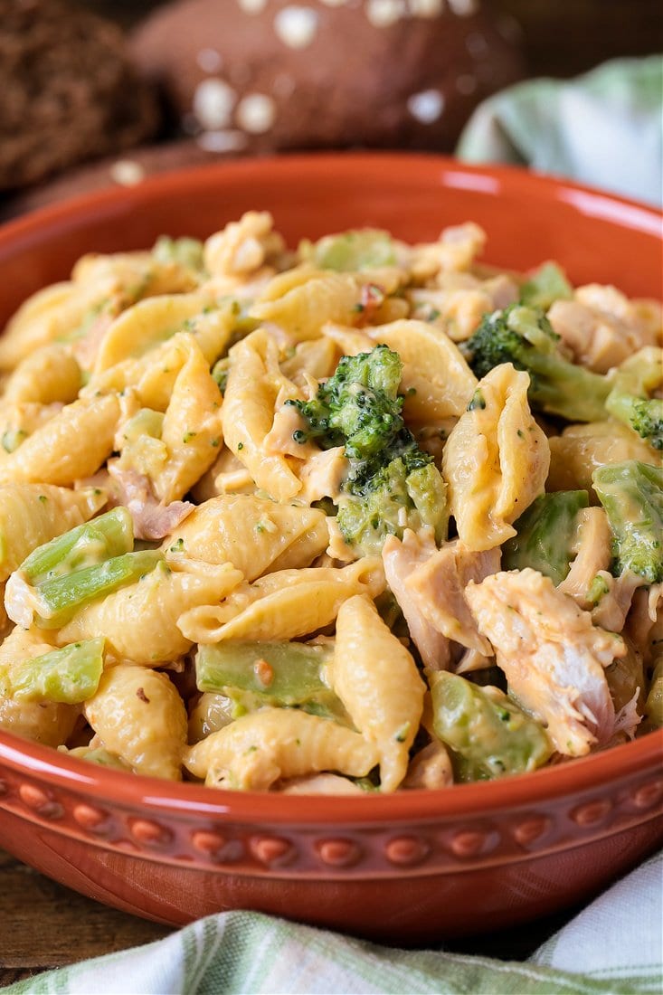 Chicken broccoli pasta in brown bowl with rolls