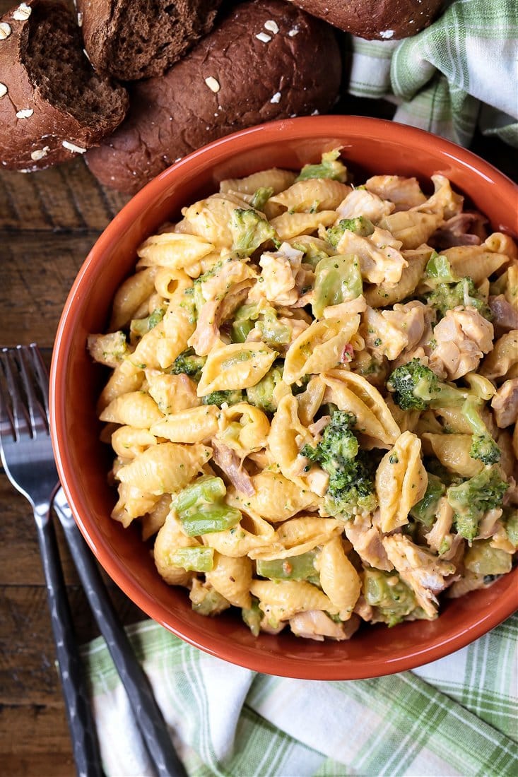 Chicken broccoli pasta in bowl with rolls and forks