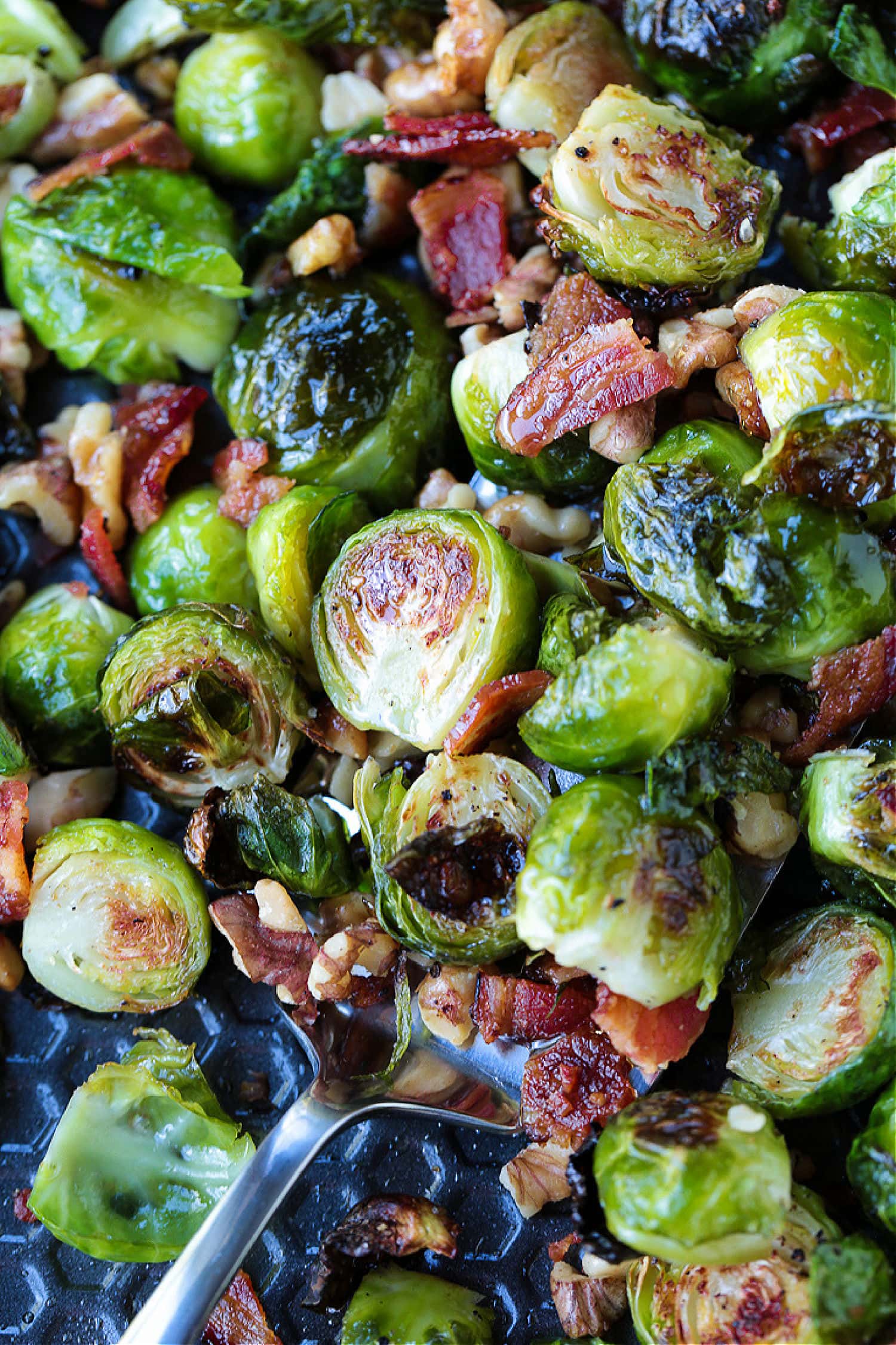 These Maple Bacon Brussels Sprouts have the perfect balance of sweet and salty! An easy to make, one pan vegetable side dish! brussels sprouts with bacon and walnuts on a sheet pan
