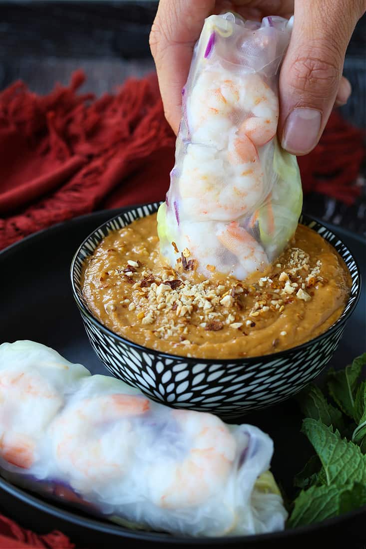 Shrimp Spring Rolls are so light and fresh – making them at home is easier than you think! Serve with our addicting peanut sauce for dipping! Vietnamese spring roll being sipped into peanut sauce