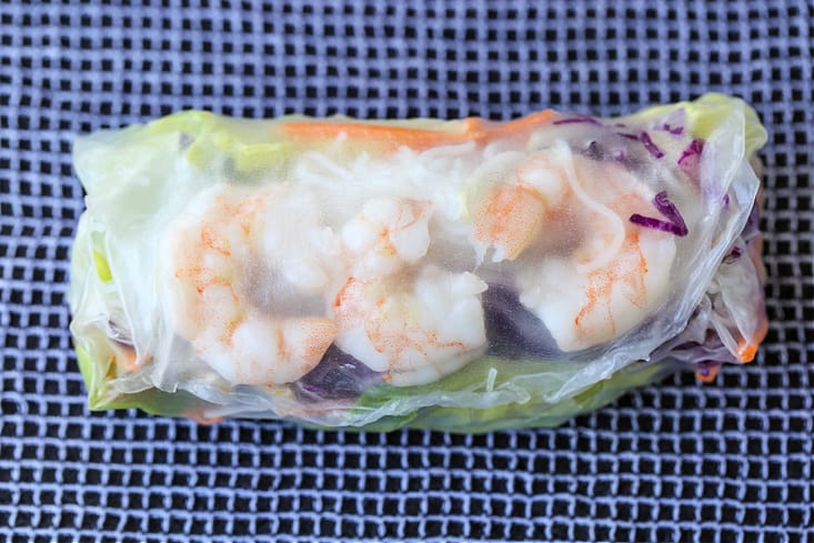 Shrimp Spring Rolls are so light and fresh – making them at home is easier than you think! Serve with our addicting peanut sauce for dipping! shrimp spring roll wrapped on a damp towel