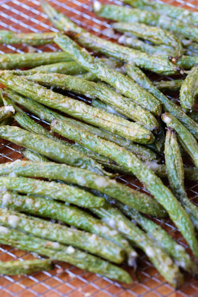 cooked green beans on an air fryer basket