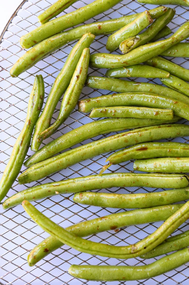 green beans tossed with seasonings on an air fryer rack