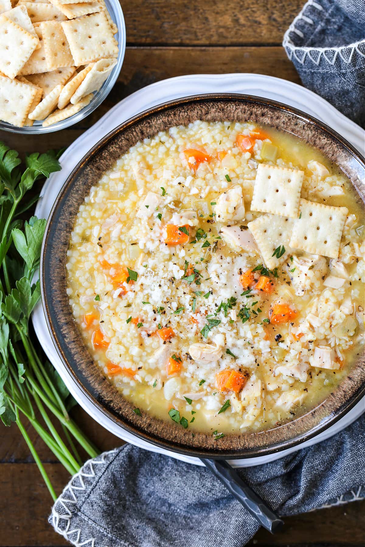 chicken pastina soup in brown bowl with crackers