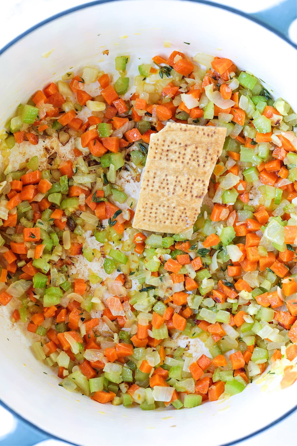 diced carrots, celery and onions in a pot with a parmesan cheese rind