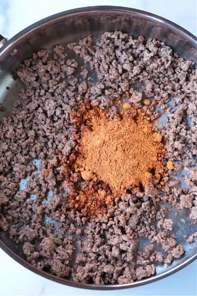 ground beef in a skillet with seasoning