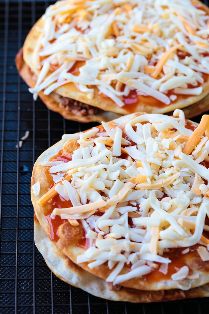 shredded cheese and enchilada sauce on top of mexican pizzas