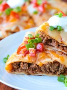 mexican pizza stacked on a plate with sour cream