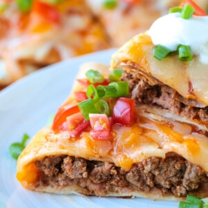 mexican pizza stacked on a plate with sour cream