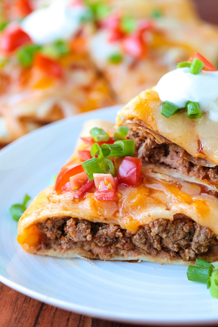 mexican pizza stacked on a plate with sour cream